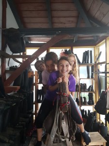 Mehrere Mädchen sitzen auf einem Übungspferd aus Holz und lachen in die Kamera.